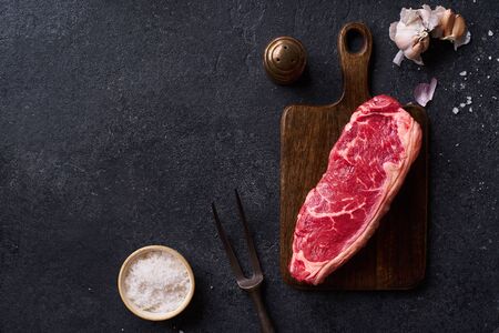 Top view Black Angus prime beef striploin steak on cutting board concrete background copy space. Flat lay cooking ingredientの写真素材