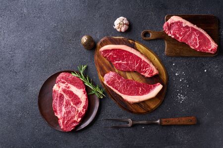 Top view variety of fresh Black Angus Prime raw beef steakes: ribeye, striploin, chuck roll and picanha on cutiing boards copy spaceの写真素材