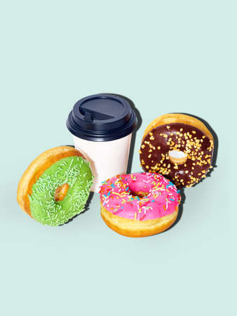Sweet glazed donuts and a coffee cup isolated on blue background with copy space. Junk food...