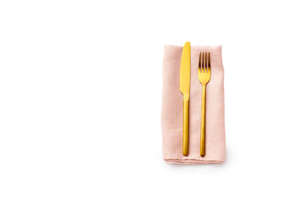 Flat lay with golden fork and knife on folded pink linen napkin isolated on white background. Top view cutlery with copy spaceの写真素材