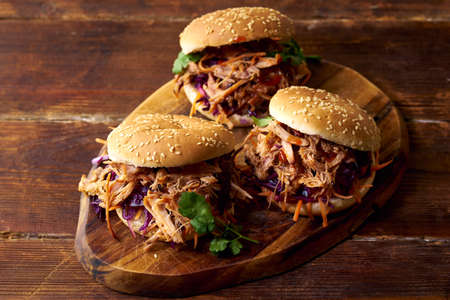 Pulled pork burgers with pickled and fresh vegetables and coriander on brown wooden backgroundの写真素材