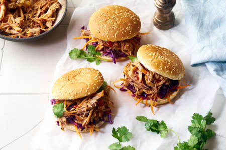 Pulled pork burgers with pickled and fresh vegetables and coriander on white tiled backgroundの写真素材