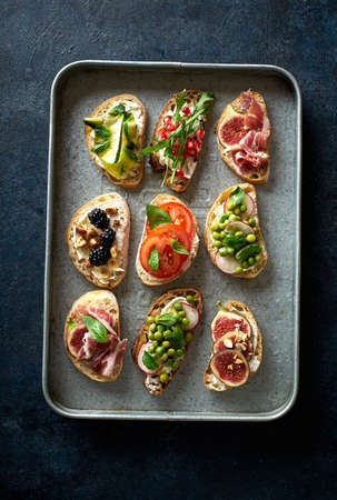 Top view of various bruschettas with toppings on metallic tray. Snack finger food meal for wine, starter.の写真素材