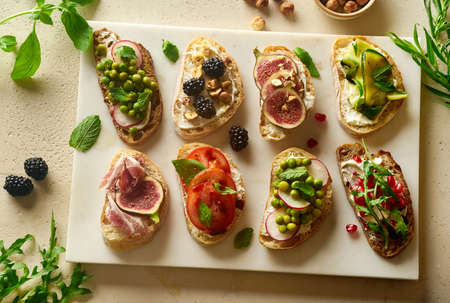Overhead of various bruschettas with toppings: ham, figs, cheese. Snack finger food meal for wine,...
