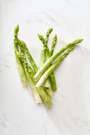 Fresh green asparagus on white marble table. Flat lay with vegan food ingredient healthy food from...