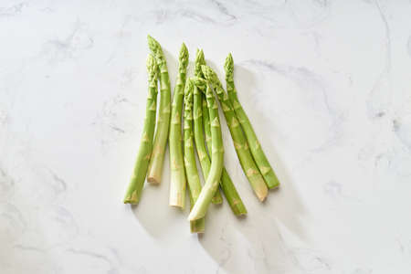 Fresh green asparagus on white marble table. Flat lay with vegan food ingredient healthy food from aboveの写真素材
