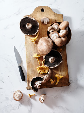 Top view various mushrooms on a wooden cutting board: portobello, champignons, chanterellesの写真素材