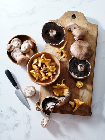 Top view various mushrooms on a wooden cutting board: portobello, champignons, chanterellesの写真素材