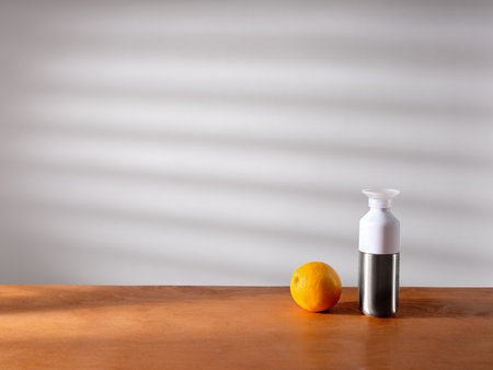 A bottle and an orange on the kitchen counter in sunlightの写真素材