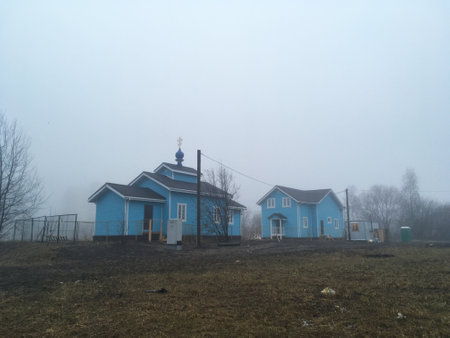 blue church on a field on a foggy day in autumnの写真素材
