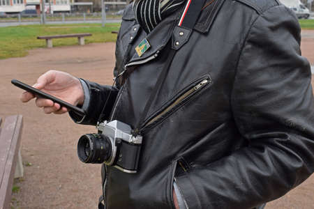 photographer holding phone and vintage old film cameraの写真素材