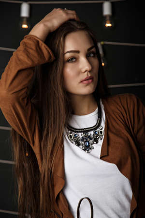 brunette posing in a hotel room sitting in purple chair on her wearing a blue sweater and jeans