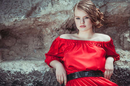portrait of a beautiful young  girl in a red dress outdoors at the day timeの写真素材