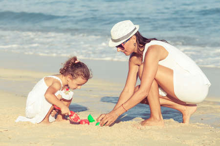 Mother and daughter playing on the beach at the day time. Concept of friendly family.の写真素材