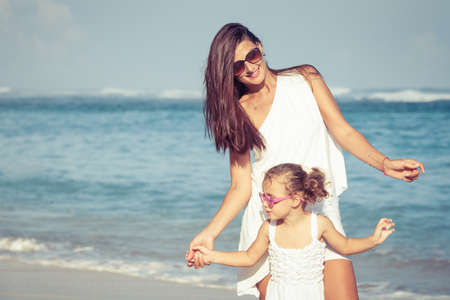 Mother and daughter playing on the beach at the day time. Concept of friendly family.の写真素材