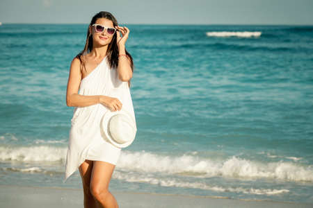 Fashion Lifestyle, Beautiful girl in the sunglasses and white hat on the beach at the day time. Travel and Vacation.の写真素材