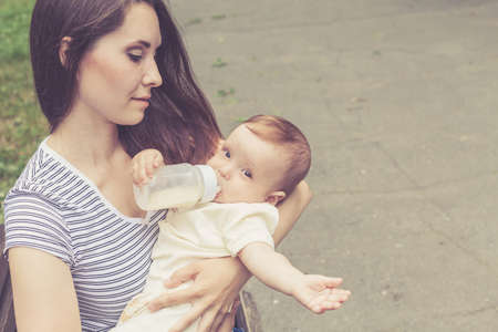 Happy mother playing with her baby in the park at the day timeの写真素材