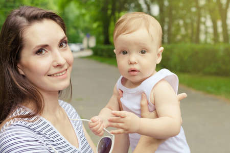 Happy mother playing with her baby in the park at the day timeの写真素材