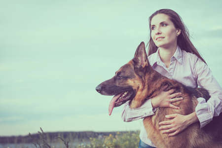 Young beautiful girl with a German shepherd playing on the lawn at the day timeの写真素材