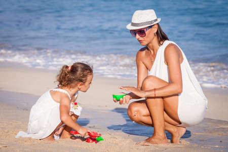 Mother and daughter playing on the beach at the day time. Concept of friendly family.の写真素材