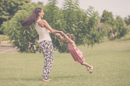 Mother and daughter playing on the grass at the day time. Concept of friendly family.の写真素材