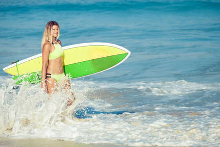 Beautiful Surfer Girl walking on the Beach at the day timeの写真素材