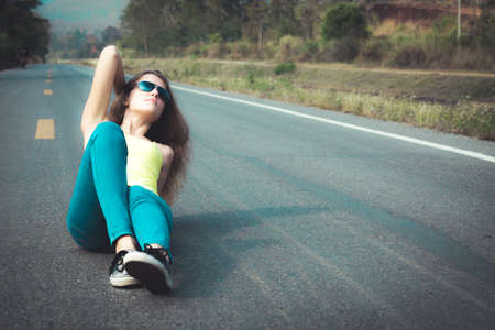 Trendy Hipster Girl in the sunglasses Relaxing on the road at the day time. Concept of Modern Youth Lifestyle .の写真素材