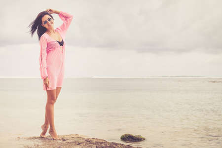 portrait of a beautiful brunette girl  in sunglasses on the beach at the day timeの写真素材