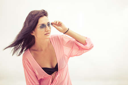 portrait of a beautiful brunette girl  in sunglasses on the beach at the day timeの写真素材