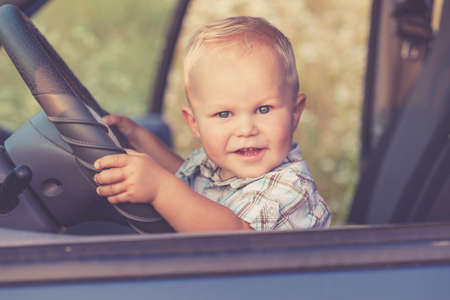 One little  boy sitting in the car and look out from the car window at the day time. Concept of happy trip.の写真素材