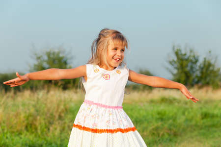 One happy little girl playing in park at the day time. Child having fun on the nature. Concept of happiness.の写真素材