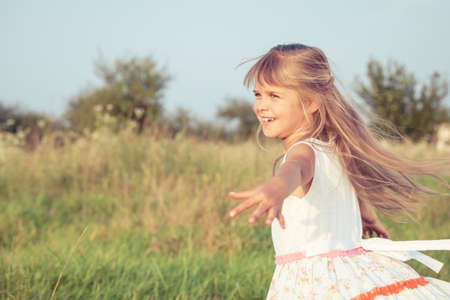 One happy little girl playing in park at the day time. Child having fun on the nature. Concept of happiness.の写真素材