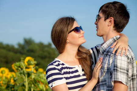 Portrait of young couple standing with sunflowers in a field. Concept of beautiful couple in love.の写真素材