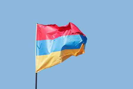 Armenian flag flying on flagpole on blue sky background