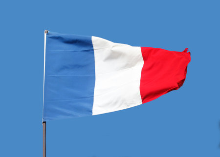 French flag flying on flagpole on blue sky backgroundの写真素材