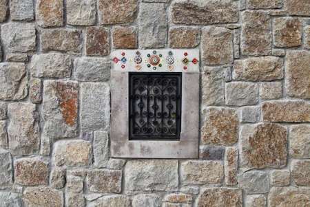 Traditional little iron window of a stone building with ornamentsの写真素材