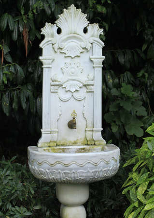 Old, ornate, embossed marble, ottoman fountain in the forest surrounded with plants