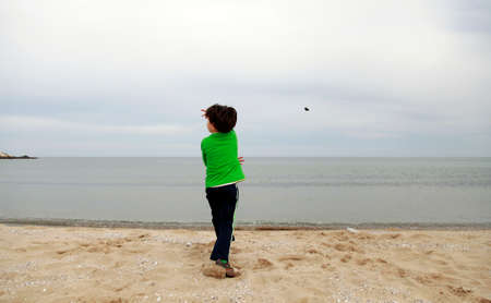 A young boy throwing a stone into the seaの写真素材