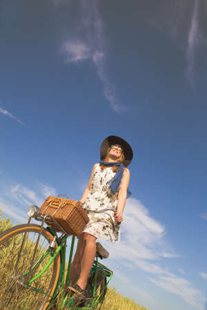 Beautiful young woman riding bicycle in a fieldの写真素材