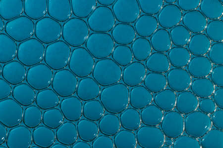 macro bubbles in water illuminated by a beam of light on a blue backgroundの写真素材