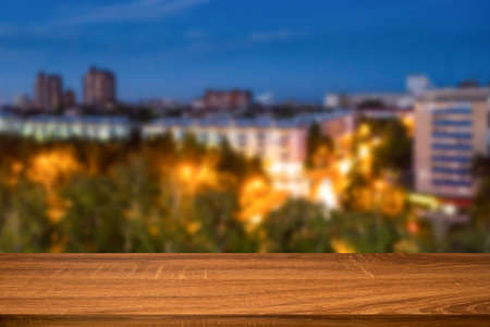 Empty wooden table with blurred background of night city. Can be used for display or montage...