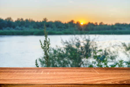 Empty wooden table with summer background of riverside at sunset. Can be used for display or montage productsの写真素材