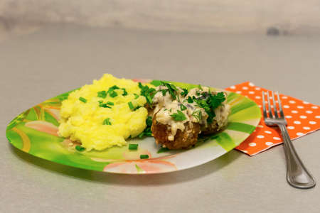 Fried meatballs with stroganoff gravy and mashed potatoes and fresh herbs on a tableの写真素材