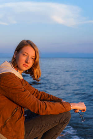 Portrait of young beautiful lady admiring the summer landscape of lake Baikal at sunsetの写真素材