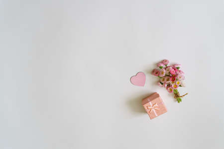 Summer creative composition in minimal style. White and pink Marguerite daisy flowers bouquet with heart and gift box on white background. Top view, flat lay, copy spaceの写真素材