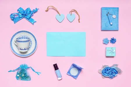 Stylish feminine accessories, flowers, cosmetics, gifts and decorative items in blue pastel colors on pink background. Empty blue card for text, mock up. Women's or mother's day concept. Flat lay.の写真素材