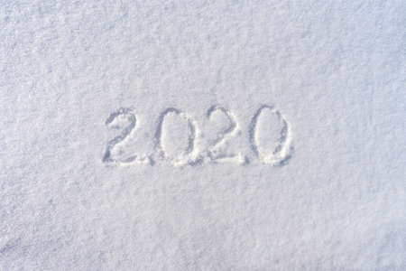 Text 2020 written on white fresh snow in sunny winter day. Merry Christmas and Happy New Year. Winter holiday concept.の写真素材
