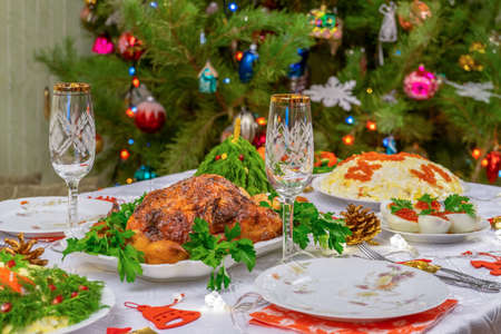 Festive Christmas served table against beautiful green pine tree decorated with many colorful new year toys. Xmas dinner, delicious food, christmas turkey. Winter holidays celebration at cozy home.の写真素材