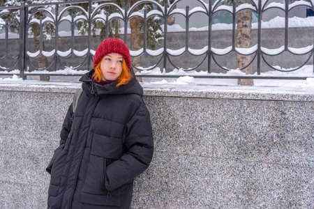Teen girl wearing casual clothes walking on snow covered city street in winter. Young lady spending...