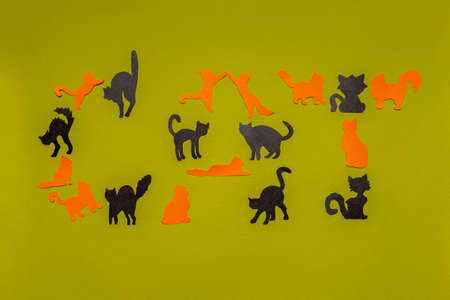 Happy National Cat Day. Word CAT made of black and orange funny silhouettes on light green...